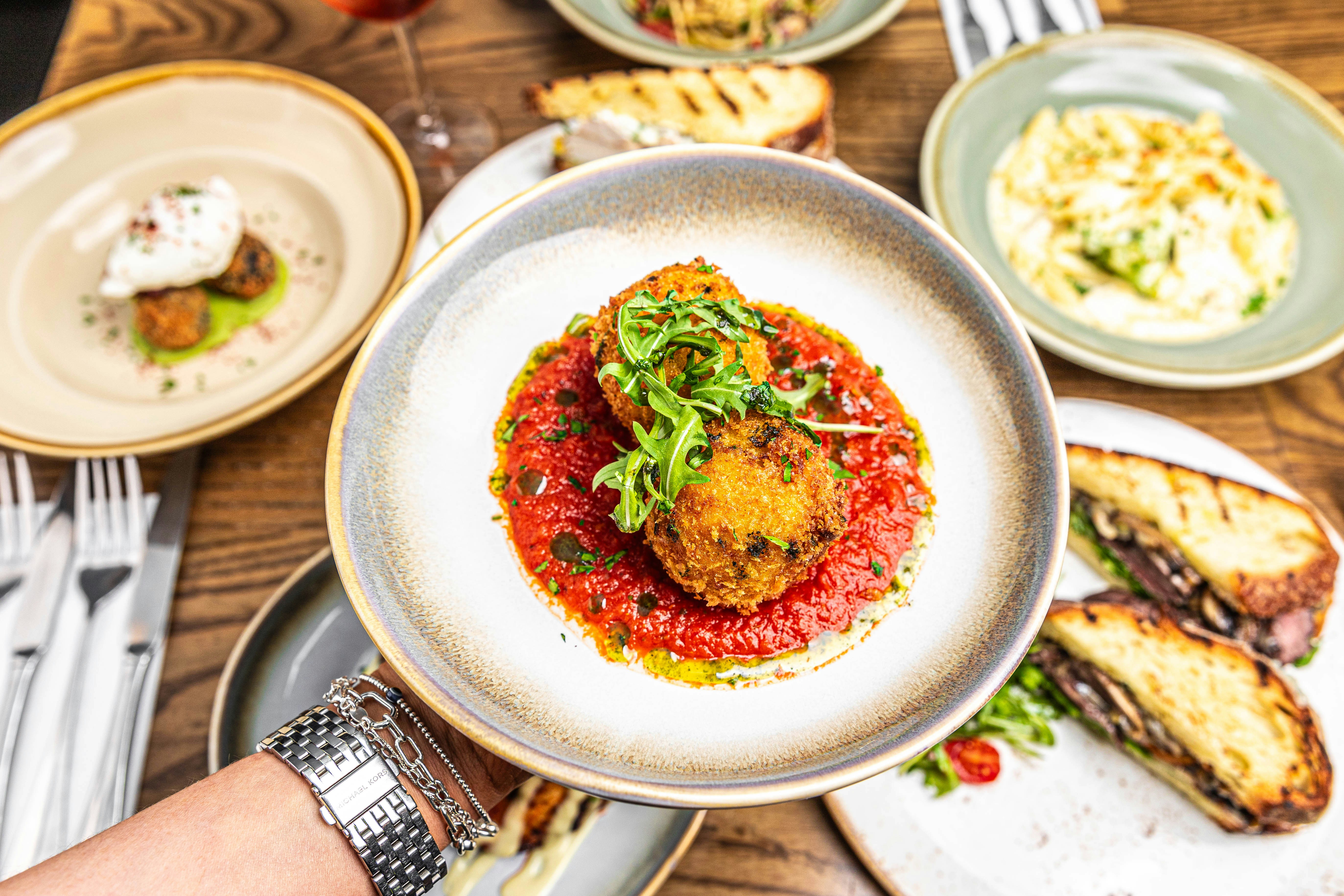 danie ze smażonymi ryżowymi kulkami arancini, położne na sosie pomidorowym, propozycja podania 